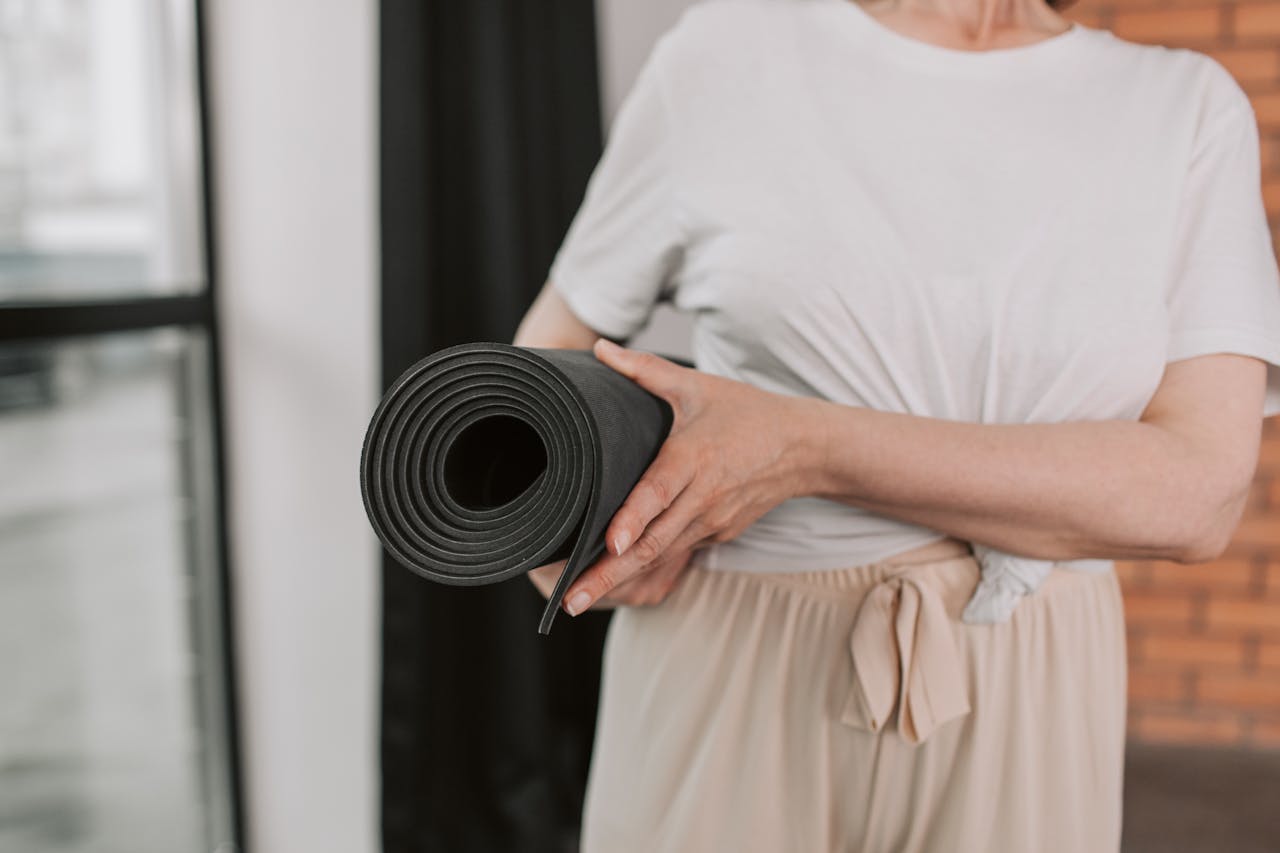 About Close-up of a senior woman holding a yoga mat, ready for a session in a modern studio.